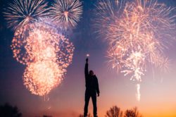 silhouette of a man outdoors, with holiday fireworks around him