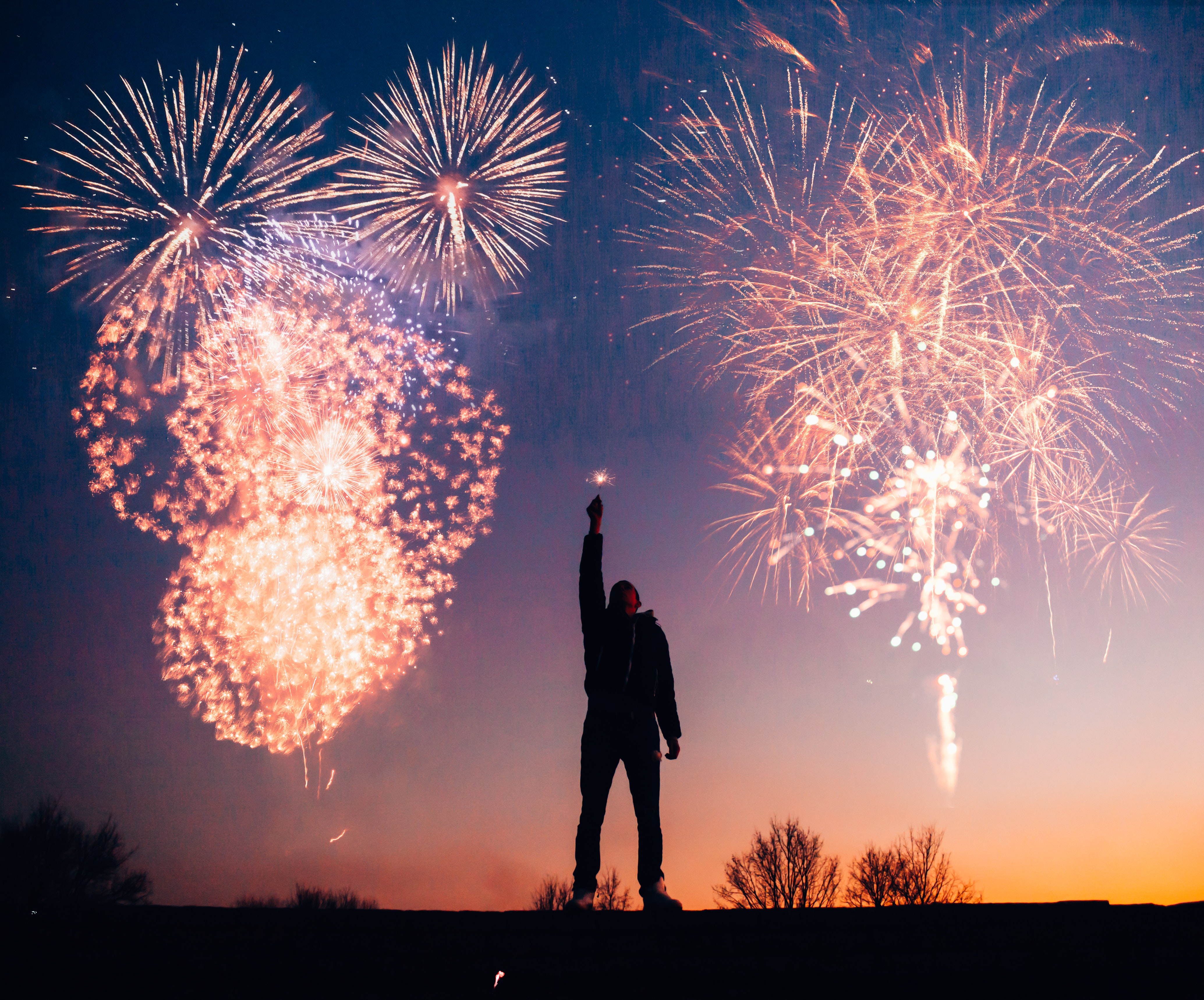silhouette of a man outdoors, with holiday fireworks around him