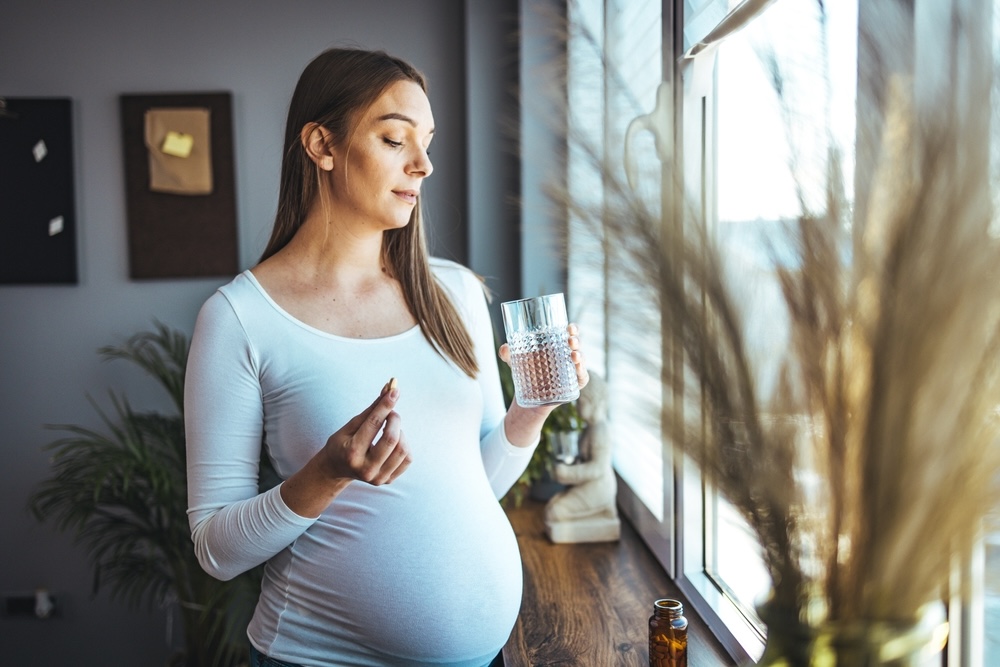 A pregnant woman taking trazodone pills and glass of water