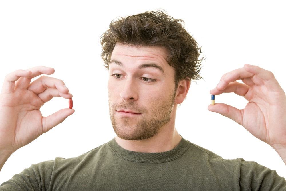 A young man in green T-shirt compares two capsules