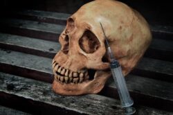 A skull and a syringe on a block surface