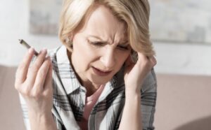 Woman with a hangover holding a weed joint
