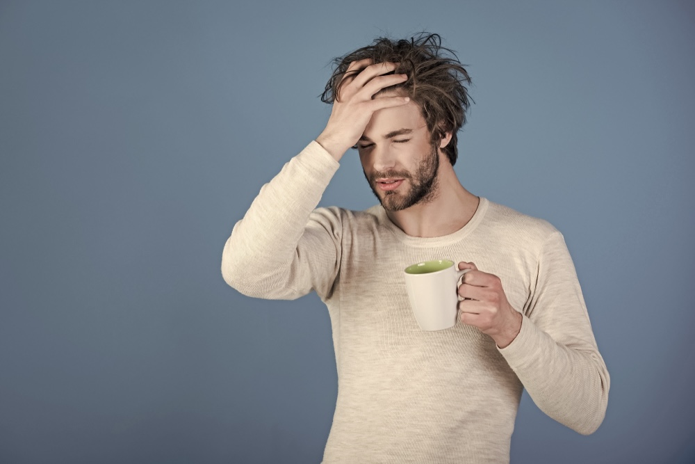 Man with a hangover holding a mug