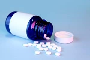 White alprazolam pills from a blue drug bottle