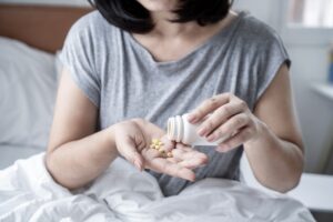 Female in bed pouring Trazodone pills on her hand