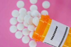Orange pill bottle with Trazodone bottle, white pills pouring out