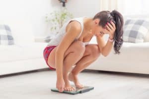 Woman on a weighing scale, on a seated position