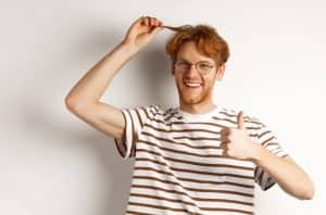 Man holds up his red hair while doing an o a thumbs up sign