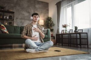 Man meditating inside the living room with headphones