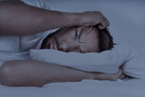 Adult male clutch his head while lying in bed after using shrooms