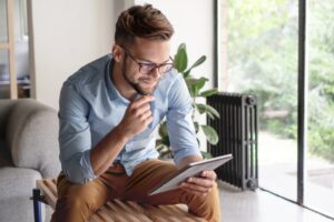 Adult man sitting on a stool in the living room reading inspiring addiction recovery quotes