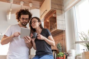Young couple standing in the kitchen reading recovery motivational quotes from a tablet