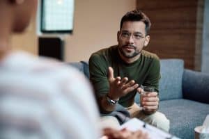 Man wearing green shirt and glasses talking to an addiction specialist about cocaine addiction