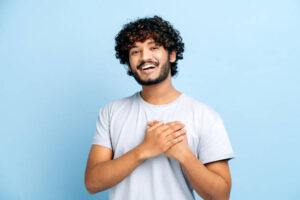 Man in a blue shirt practicing gratitude during the holidays putting his hands over his heart