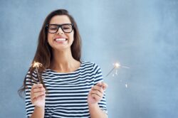 Female wearing eyeglasses holding sparklers smiling during New Year