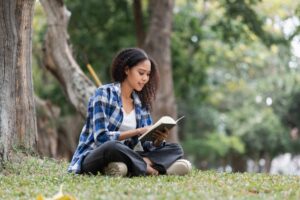 Woman sitting outdoors reading her journal to set New Year intentions
