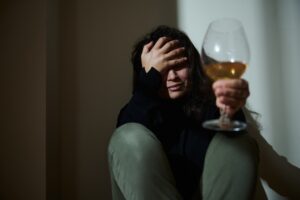 Depressed woman crying holding a glass of wine needing help