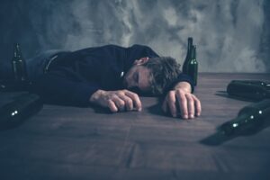Man on the floor with empty beer bottles unconscious from alcohol poisoning
