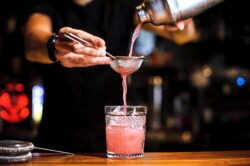 Bartender mixing a Pink Whitney drink in a dimly lit bar