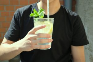 A man in a black shirt holding a non-alcoholic lemonade drink during the summer season