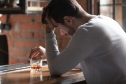 Man looking upset holding a glass of alcohol