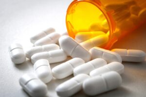 White hydrocodone pills spilling out of the orange medicine bottle