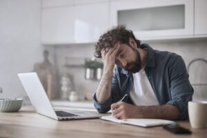 Man in drug addiction recovery stressed while working on his laptop