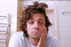 Man with alcohol use disorder looking at his puffy face in the mirror